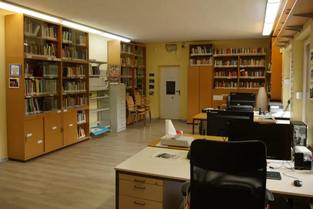 Innenansicht der Präsenzbibliothek im Archiv Rom e.V. mit Bücherregalen, Schreibtischen und Arbeitsplätzen für Besucher:innen